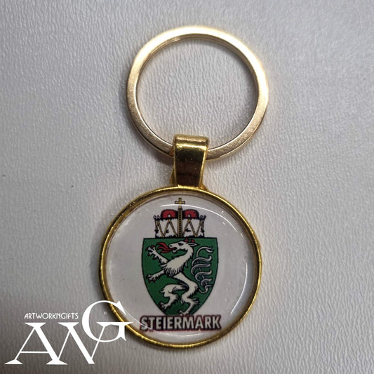 the Styrian panther emblem and the text "STEIERMARK".Austria Uhrturm Handmade necklace keychain 25 mm gold